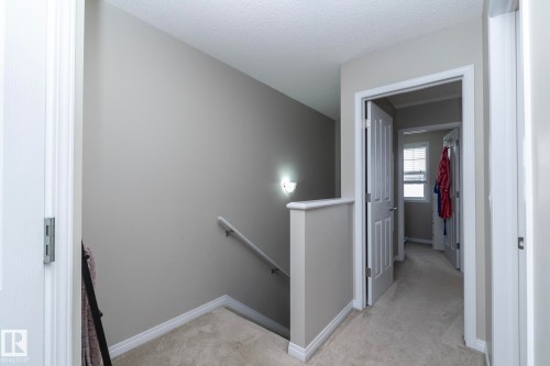 Hallway featuring light neutral wall paint, carpeted flooring, white trim, and interior doors with white paneling - 46 4050 Savaryn Drive, Edmonton, AB 