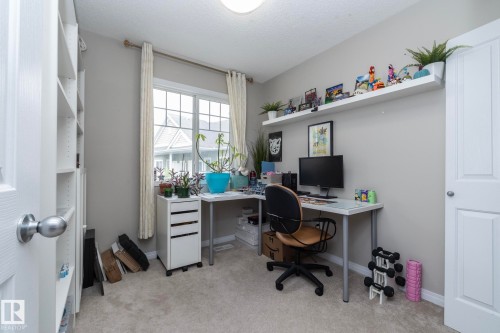 Spacious room featuring neutral-toned walls, plush carpeting, and a large window providing natural light - 46 4050 Savaryn Drive, Edmonton, AB 