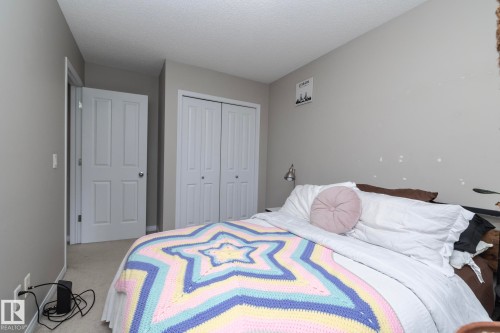 Carpeted bedroom featuring neutral wall tones and a textured ceiling - 46 4050 Savaryn Drive, Edmonton, AB 