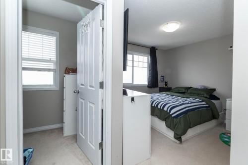 Carpeted bedroom featuring neutral wall tones, a double-paned window, and a flush-mount ceiling light fixture - 46 4050 Savaryn Drive, Edmonton, AB 