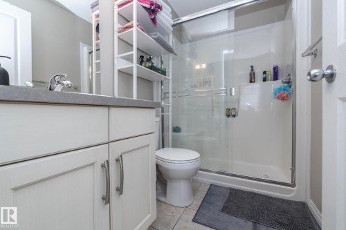Bathroom featuring a single vanity with a stone countertop, white shaker-style cabinetry, and a chrome faucet - 46 4050 Savaryn Drive, Edmonton, AB 