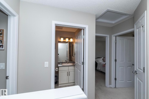 Interior hallway featuring neutral wall paint, white trim, and a textured ceiling - 46 4050 Savaryn Drive, Edmonton, AB 