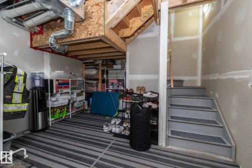 Finished basement area with striped flooring, exposed ceiling joists, and visible HVAC ductwork - 46 4050 Savaryn Drive, Edmonton, AB 