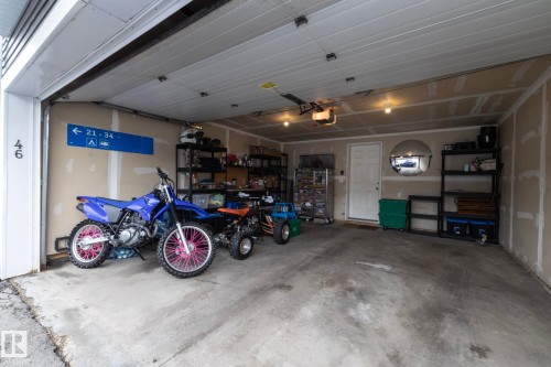 Attached garage featuring a concrete floor, exposed drywall walls, overhead lighting, and an automatic garage door opener - 46 4050 Savaryn Drive, Edmonton, AB 