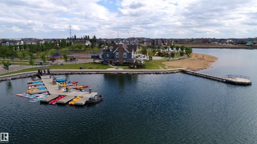 Expansive lakefront setting featuring a private beach area, a dock with multiple watercraft, and a clubhouse - 46 4050 Savaryn Drive, Edmonton, AB 