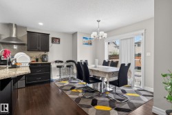 Open-concept kitchen and dining area featuring dark wood-finish flooring, granite countertops, and dark cabinetry - 
