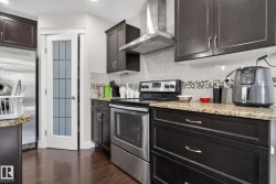 Kitchen featuring dark wood-finish cabinetry, stainless steel appliances, granite-style countertops, and a subway tile backsplash with a decorative accent band - 