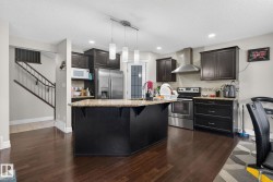 Kitchen featuring dark wood-finish cabinetry, stainless steel appliances, a center island with a light-toned countertop, and dark wood-finish flooring - 