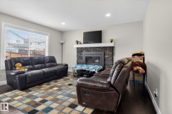 Living room featuring a dark stone-clad fireplace with a white mantel, dark wood-finish flooring, and recessed ceiling lighting - 