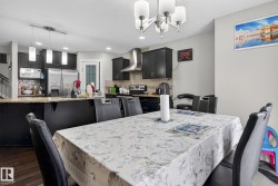 Open-concept kitchen and dining area with dark wood-finish cabinetry and a complementary light-toned countertop - 