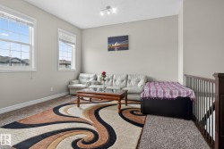 Carpeted bonus room featuring two large windows with white blinds, neutral wall paint, and a brown wood handrail with dark metal spindles - 