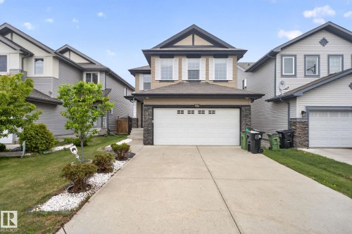Contemporary two-story residence featuring a dual-tone facade, attached front-facing garage, concrete driveway, and landscaped front yard with decorative white stone accents - 3350 18B Street, Edmonton, AB 
