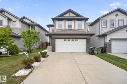 Contemporary two-story residence featuring a dual-tone facade, attached front-facing garage, concrete driveway, and landscaped front yard with decorative white stone accents - 