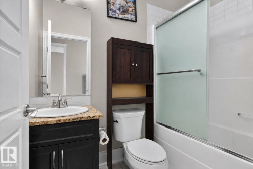 Bathroom featuring a black vanity with a beige speckled countertop, undermount sink, and polished chrome faucet - 3350 18B Street, Edmonton, AB 