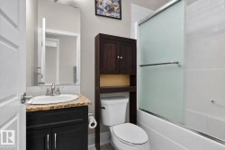 Bathroom featuring a black vanity with a beige speckled countertop, undermount sink, and polished chrome faucet - 
