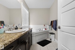 Bathroom featuring a vanity with a granite-style countertop, undermount sink, and dark wood cabinetry - 