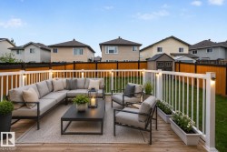 Wood-finish decking featuring a white railing with integrated lighting, a manicured lawn, and a privacy fence - 
