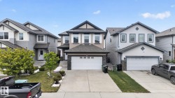 Two-story property featuring a tan and dark brown exterior, an attached two-car garage, white framed windows, and a concrete driveway - 