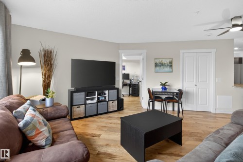 Open-concept living area featuring wood-finish flooring, a ceiling fan fixture, and neutral wall tones - 211 3719 Whitelaw Lane, Edmonton, AB 