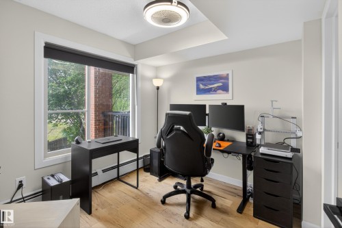 Room featuring a large window, light wood-finish flooring, neutral wall color, and a ceiling-mounted light fixture - 211 3719 Whitelaw Lane, Edmonton, AB 
