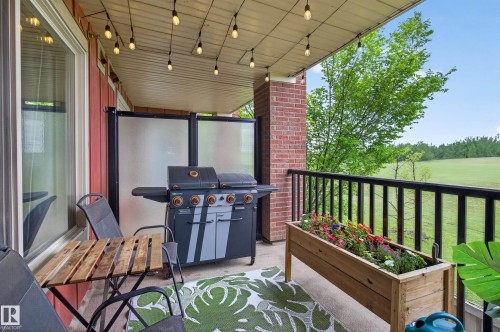 Covered outdoor patio featuring string lighting, brick accents, and privacy panels - 211 3719 Whitelaw Lane, Edmonton, AB 