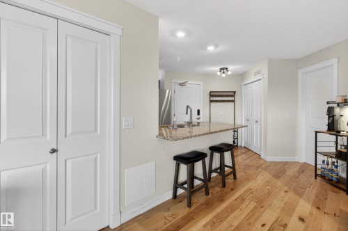 Kitchen counter with a granite-style surface, a stainless steel sink with a high arc faucet, and recessed ceiling lighting - 211 3719 Whitelaw Lane, Edmonton, AB 