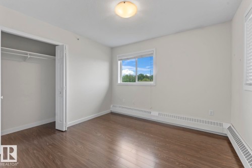 Spacious room featuring wood-finish flooring, light-colored walls, a bi-fold closet, and baseboard heating - 1302-1601 8 Avenue, Cold Lake, AB 