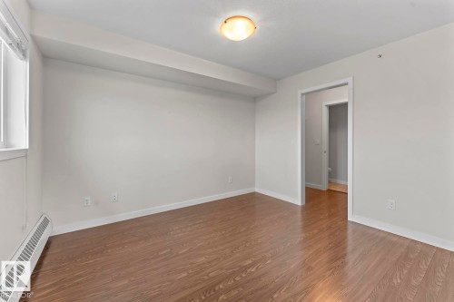 Spacious room featuring wood-finish flooring, white baseboards, and a window with blinds - 1302-1601 8 Avenue, Cold Lake, AB 