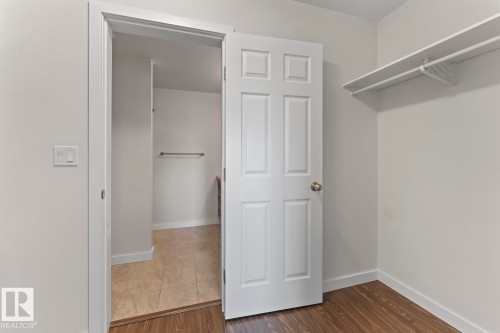 Bedroom with wood-finish flooring and a white paneled door - 1302-1601 8 Avenue, Cold Lake, AB 