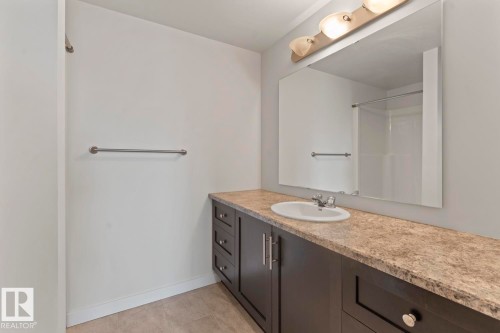 Bathroom vanity featuring a light-colored countertop, an undermount sink, and a large mirror with overhead lighting - 1302-1601 8 Avenue, Cold Lake, AB 
