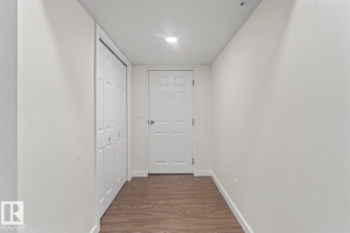 Entryway featuring wood-finish flooring, white walls, recessed lighting, and a paneled entry door - 1302-1601 8 Avenue, Cold Lake, AB 