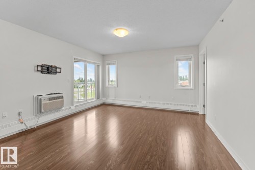 Spacious room featuring wood-finish flooring, white walls, and a ceiling-mounted light fixture - 1302-1601 8 Avenue, Cold Lake, AB 