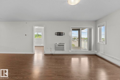 Bright open-concept living area featuring wood-finish flooring, crisp white walls, and a recessed ceiling light - 1302-1601 8 Avenue, Cold Lake, AB 