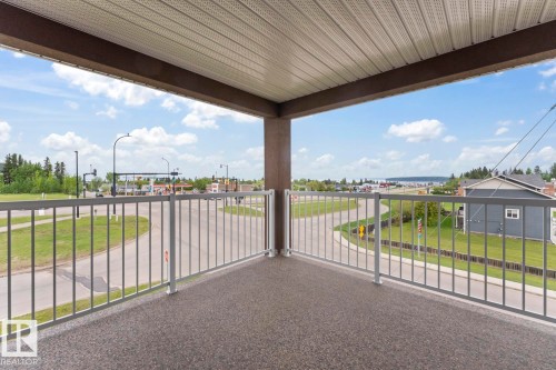 Covered outdoor balcony featuring a textured floor, white metal railing, and a slatted ceiling - 1302-1601 8 Avenue, Cold Lake, AB 