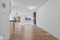 Wood-finish flooring extending into a spacious living area with a stone-clad fireplace and a white mantel - 