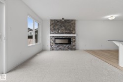 Living area featuring a floor-to-ceiling stone-faced fireplace with a contemporary electric insert and a white mantle - 