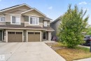 Contemporary multi-story residence featuring a two-car garage with carriage-style doors, multi-tone horizontal siding, and a gabled roofline - 3806 Powell Wynd, Edmonton, AB 