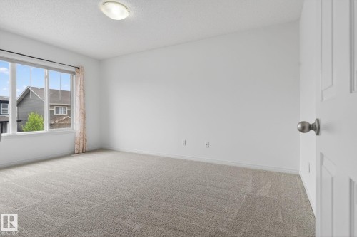 Neutral tone carpeting complements light-colored walls in this room, featuring a large window with white trim - 3806 Powell Wynd, Edmonton, AB 