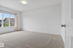 Neutral tone carpeting complements light-colored walls in this room, featuring a large window with white trim - 