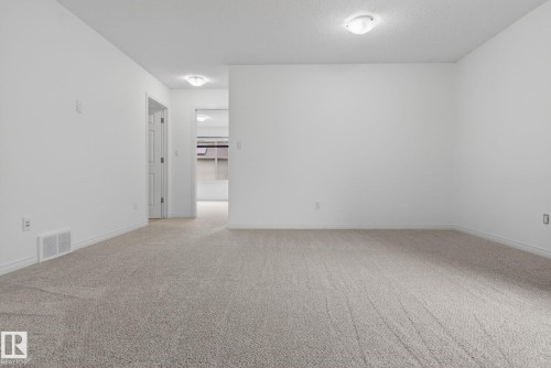 Spacious room featuring light-toned carpet flooring, white walls, and white trim - 3806 Powell Wynd, Edmonton, AB 