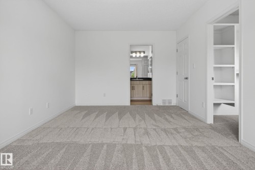 Spacious room featuring light gray patterned carpeting, white walls, and white trim - 3806 Powell Wynd, Edmonton, AB 