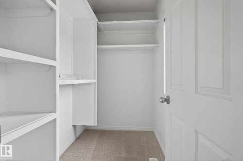 Closet featuring built-in shelving, hanging rods, and neutral carpet flooring - 3806 Powell Wynd, Edmonton, AB 