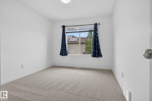 Carpeted interior space featuring white walls and a window with a white frame - 3806 Powell Wynd, Edmonton, AB 