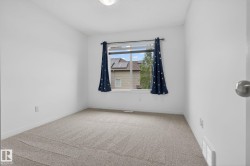 Carpeted interior space featuring white walls and a window with a white frame - 