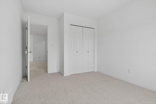 Carpeted room with a bi-fold closet, white walls, and white trim - 3806 Powell Wynd, Edmonton, AB 