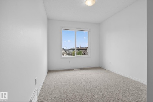 Bright interior space featuring light-colored carpeting, white wall paint, and a window with white trim - 3806 Powell Wynd, Edmonton, AB 