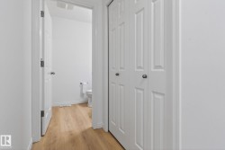 Hallway with wood-finish flooring, white walls, and white bi-fold closet doors - 