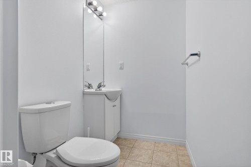 Bathroom featuring a white toilet, a vanity with an integrated sink, and a chrome-finish faucet - 3806 Powell Wynd, Edmonton, AB 