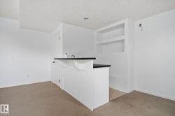 Built-in bar with a dark countertop and integrated sink, complemented by recessed shelving with accent lighting - 