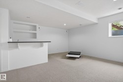 Finished basement space featuring a built-in bar with dark countertop and integrated shelving - 